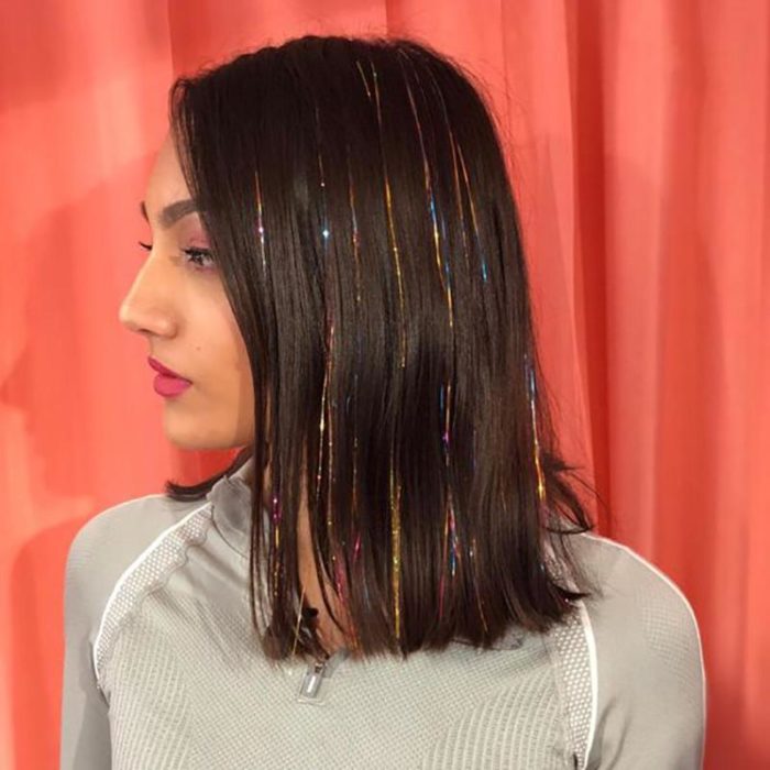 Chica usando extensiones de glitter en el cabello 