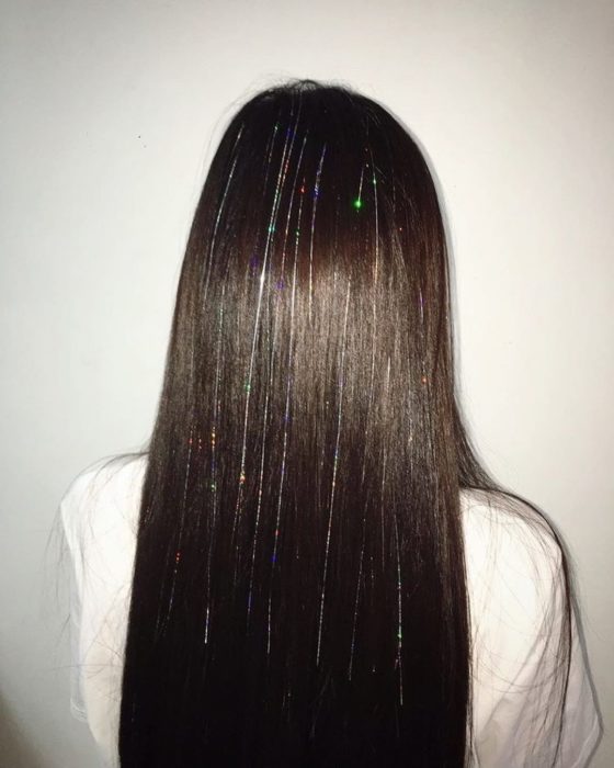 Chica usando extensiones de glitter en el cabello 