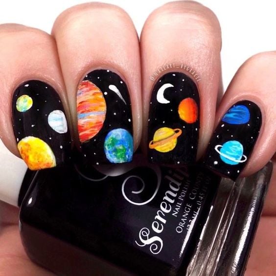 Uñas en negro con stickers del sistema solar