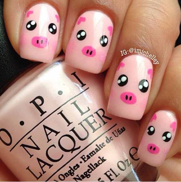 Chica con las uñas pintadas de color rosa y decoradas con un cochinito