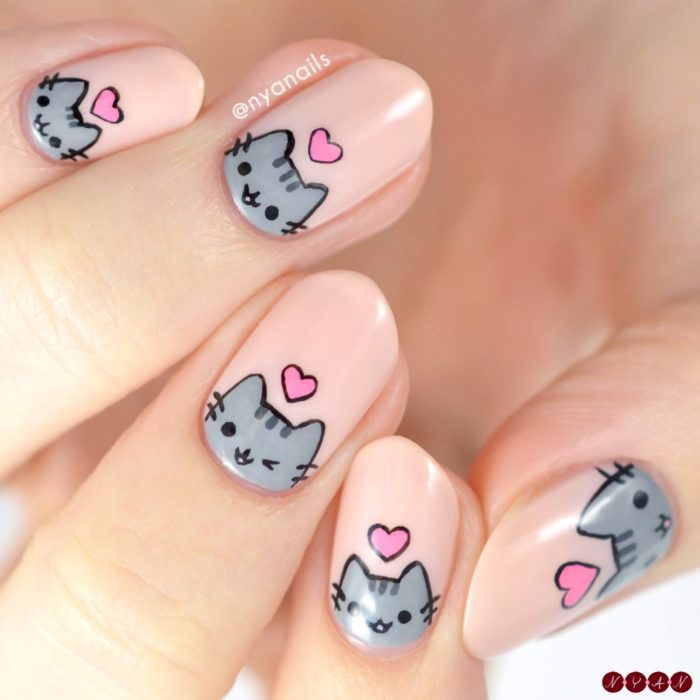 Chica con las uñas pintadas de color rosa y decoradas con un gato 