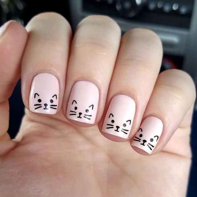 Chica con las uñas pintadas de color rosa y decoradas con un gato 