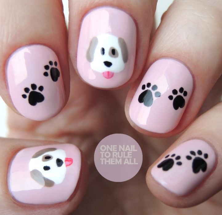 Uñas de color rosa decoradas con un perrito y huellas en color negro 