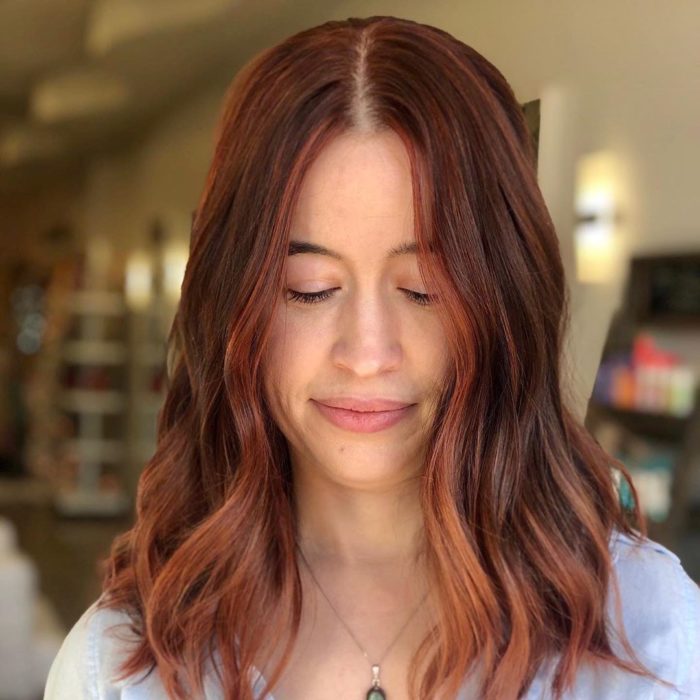 Chica con el cabello de color cobrizo y reflejos en color naranja 