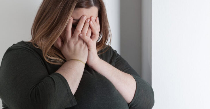 mujer con sobrepeso cubriéndose el rostro