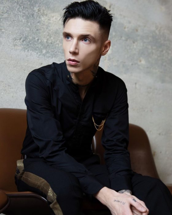 Andy Biersack sentado en un sofá posando para una fotografía