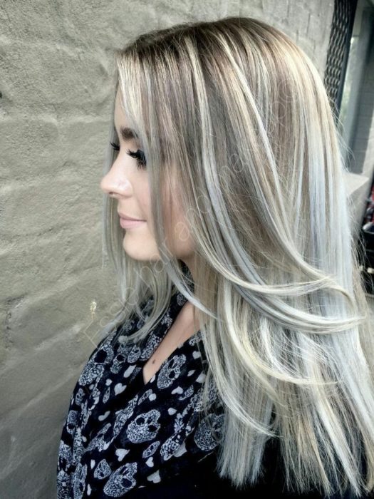 Chica con el cabello teñido en color rubio cenizo con mechas en color platinado