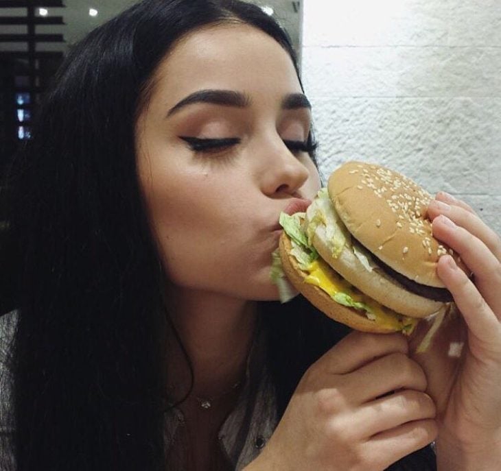 Chica comiendo una hamburguesa en un restaurante 