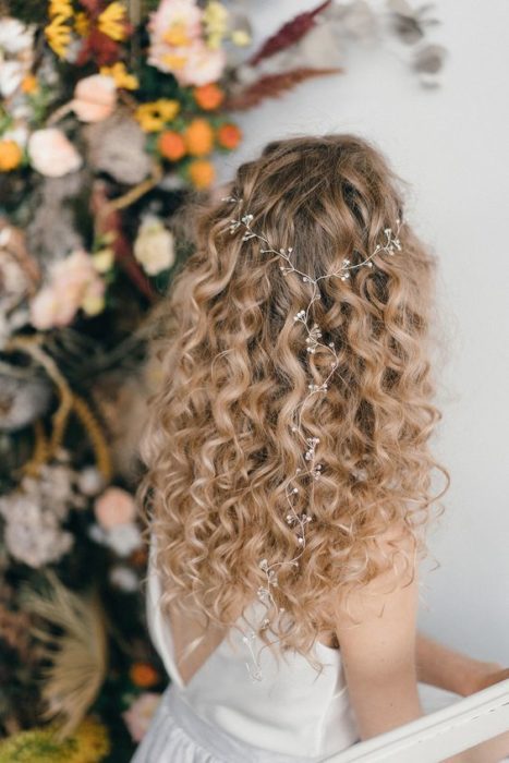 Novia con cabello rizado suelto y un tocado fino