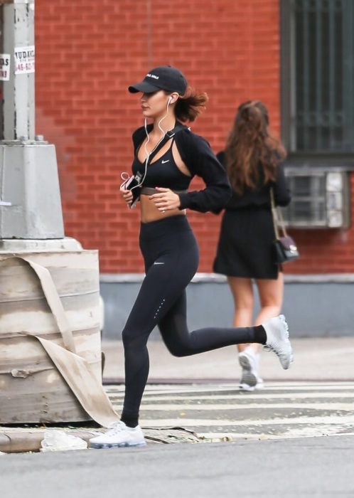 Chica trotando con ropa deportiva, escuchando música