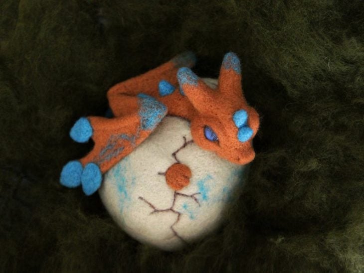 Dragón naranja recién nacido en su huevito con detalles azules