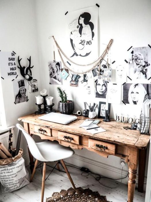 Habitación blanca, silla blanca de cuatro patas y escritorio vintage de madera, con posters pegados en la pared