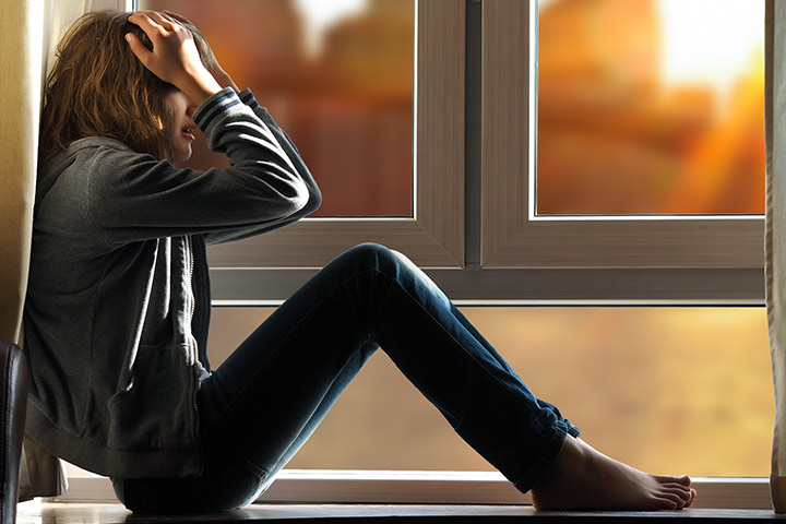 Chica estresada sentada al lado de una ventana