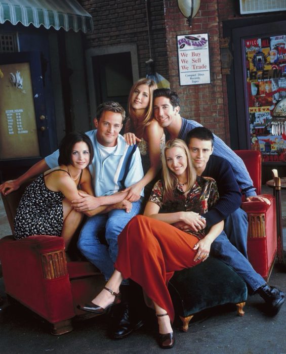 Elenco de Friends reunido en un sofá roja para una foto grupal