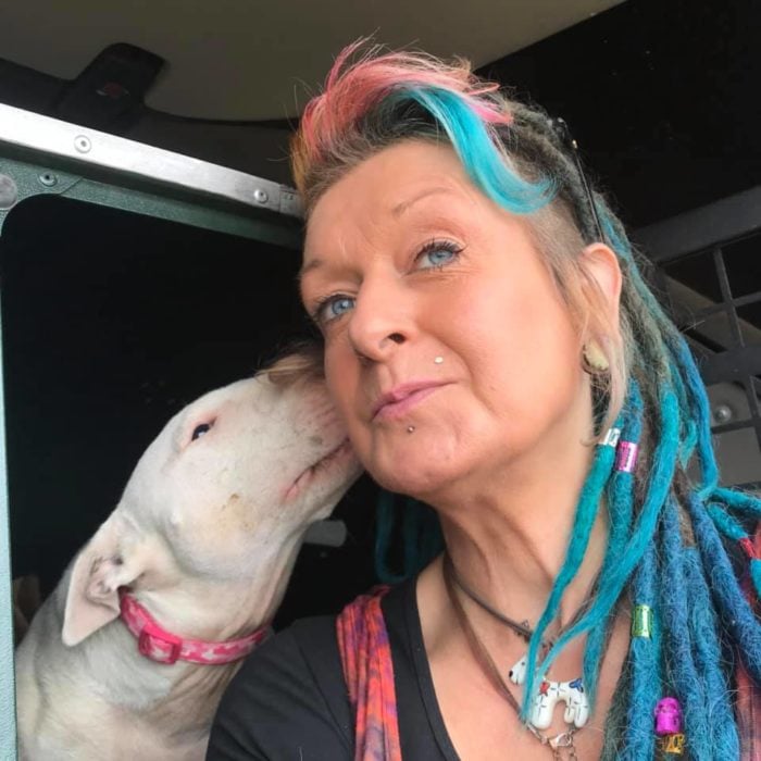 Liz con rastas azules en el cabello y un perrito besándola