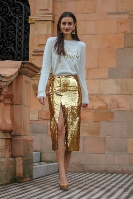 Chica usando una falda de corte lápiz de color dorado con lentejuelas 