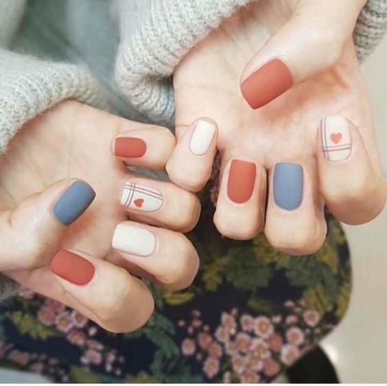 Manicura en uñas cortas en colores azul, blanco y naranja