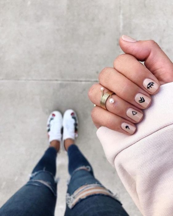 Manicura en uñas cortas de tono rosa palo con stickers negros