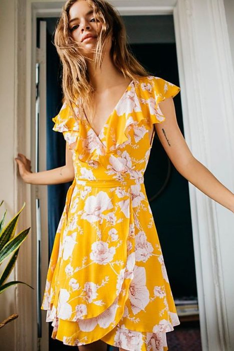 Chica con vestido amarillo y decorado con flores blancas en estilo wrap