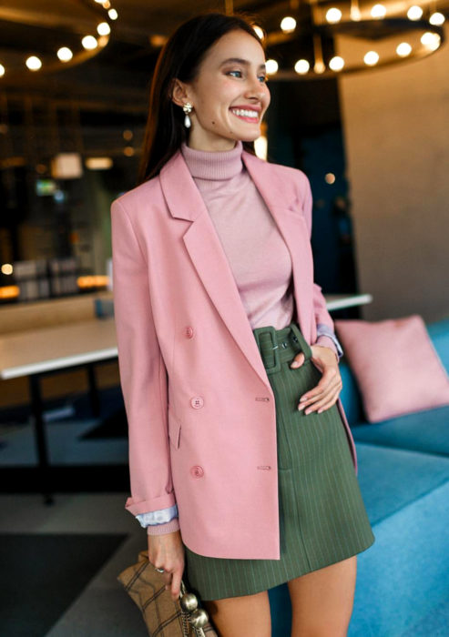 Atuendos formales y juveniles para oficina; mujer con blusa cuello de tortuga, saco rosa, falda verde