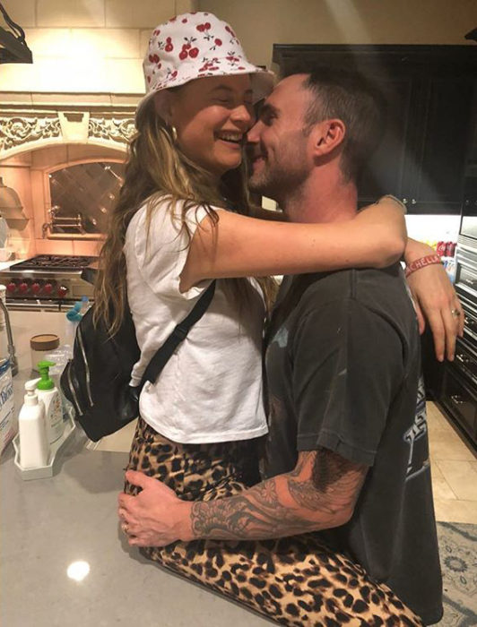 Adam Levine y Behati Prinsloo abrazados mientras están en la cocina de su casa 
