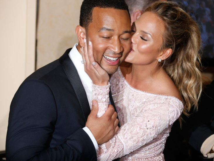 Chrissy Teigen y John Legend besándose en la alfombra roja 