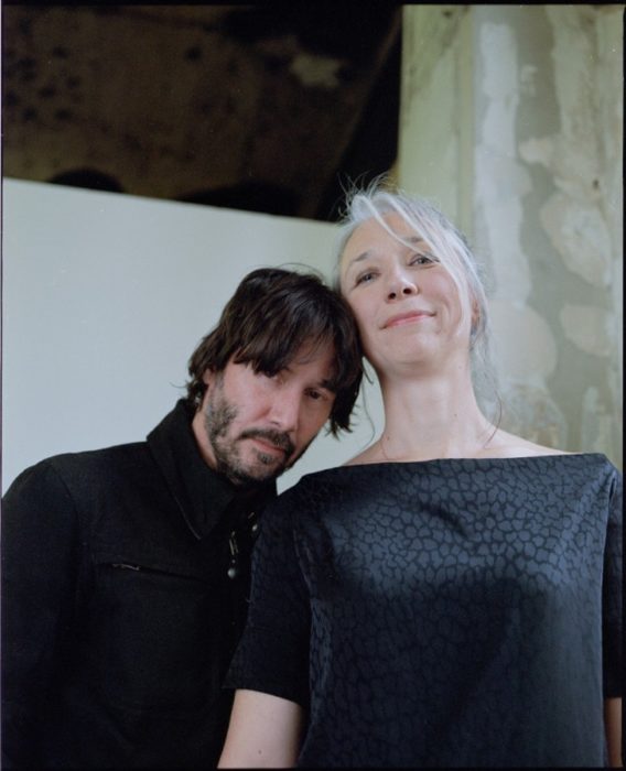 Keanu Reeves y Alexandra Grant abrazados mientras están en una galería 