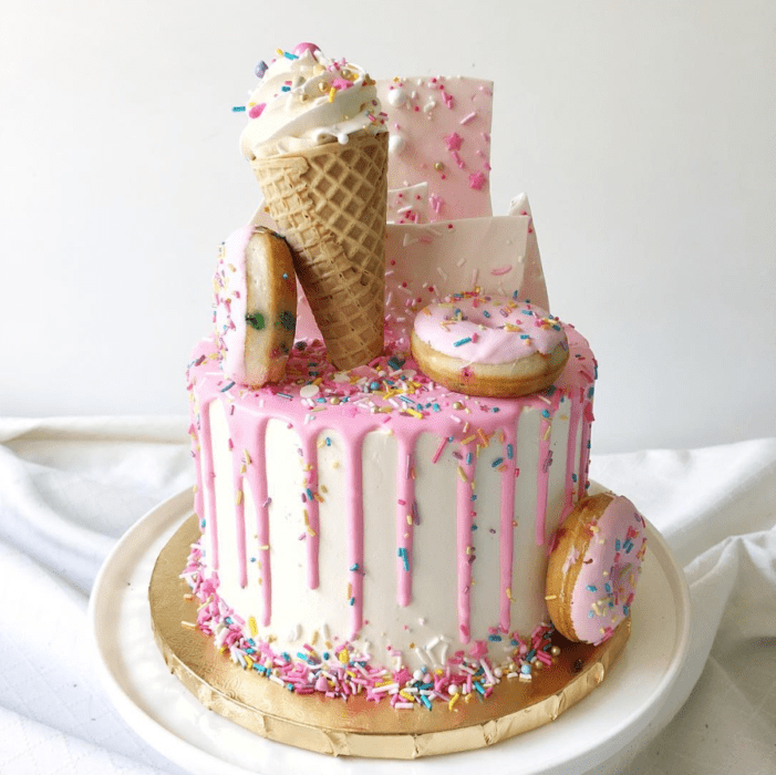 Pastel de vainilla decorado con pastelillos de donas y conos