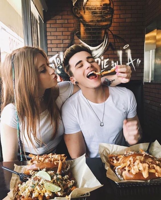 Pareja de novios comiendo papas fritas y hamburguesas 