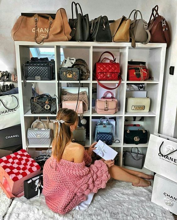 Chica sentada frente a un armario repleto de bolsos de colores