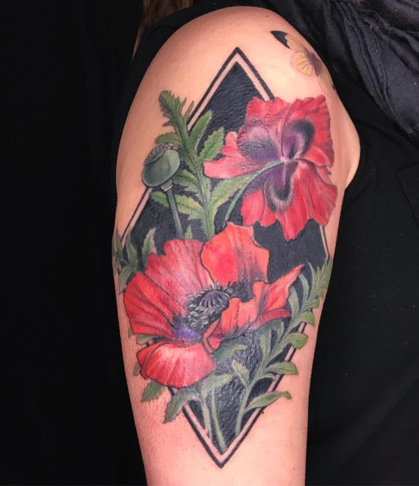 Tatuaje de flores rojas, con fondo negro de un rombo con una mariposa amarilla