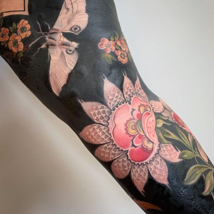 Tatuaje con fondo negro con flor y mariposa