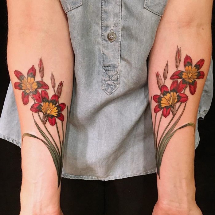 Tatuajes de flores rojas en ambos antebrazos