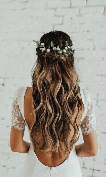 Peinado para novia de cabello rizado suelto con tocado floral