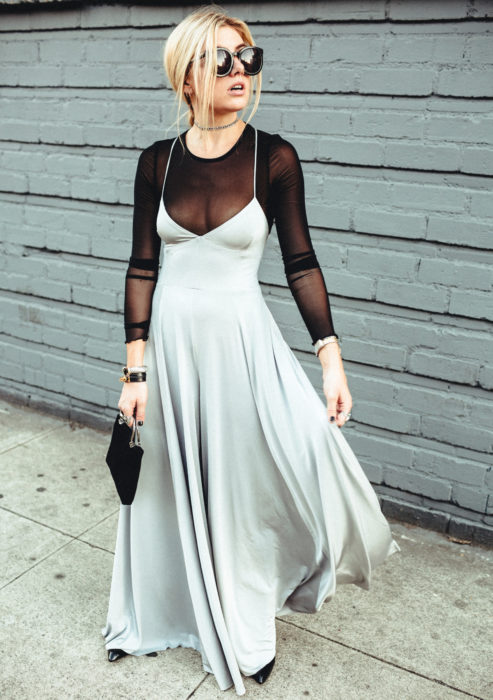 Looks con vestidos y blusas básicas; mujer rubia con peinado casual, lentes de sol grandes, blusa negra transparente, vestido de fiesta gris satinado