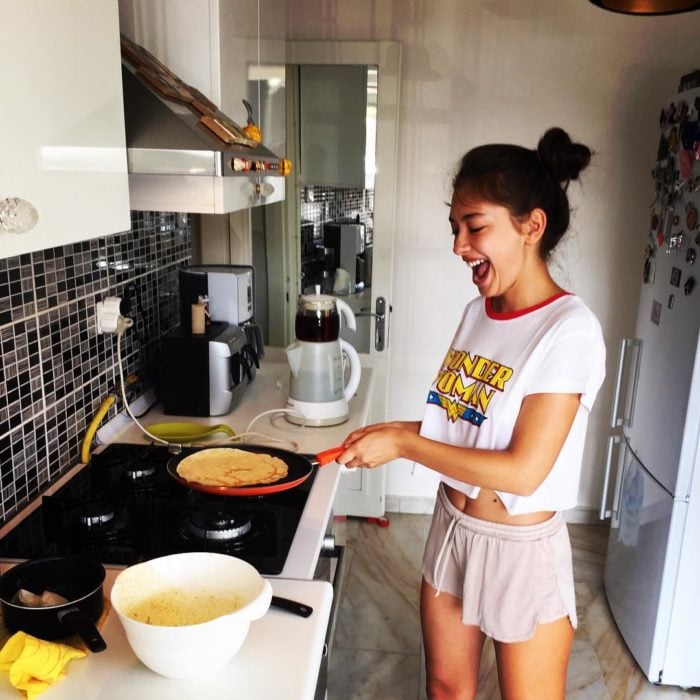 Chica cocinando el desayuno en una cocina blanca