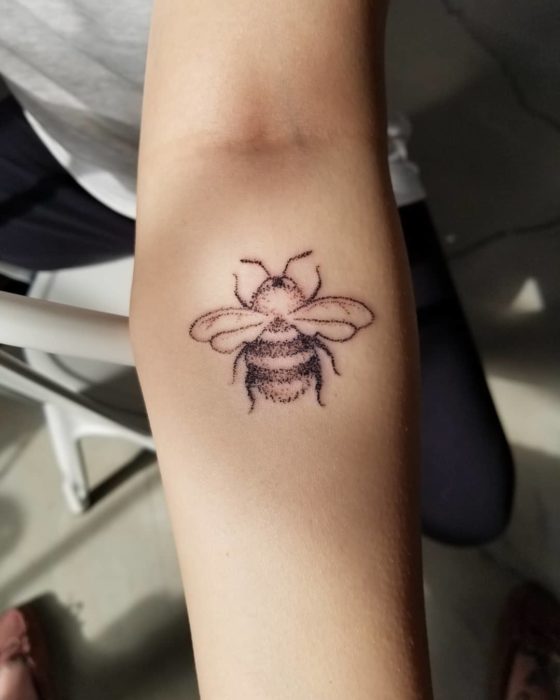 Tatuaje al estilo hand poke de abeja a una tinta en el antebrazo