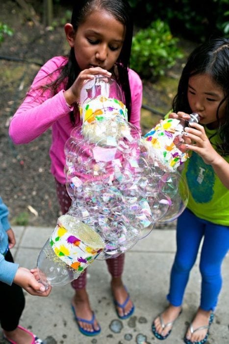 Niños hacen burbujas con botellas de plástico