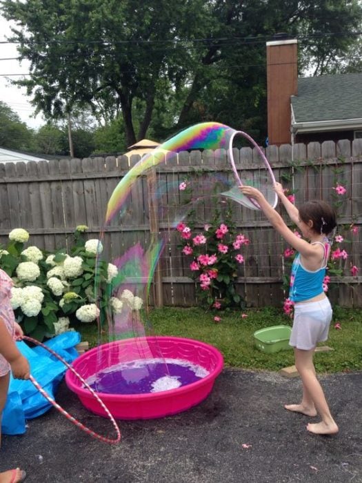 Niña jugando con burbujas gigantes