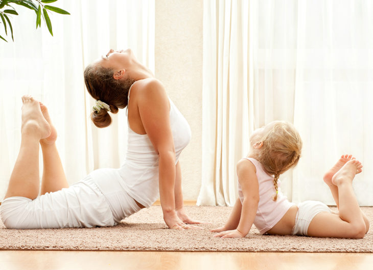 Madre e hija haciendo yoga en su sala