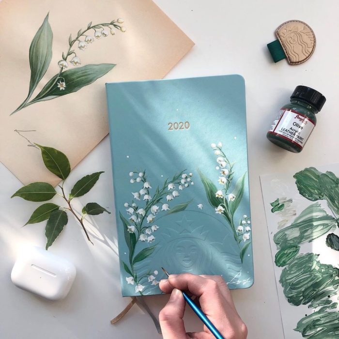 Agenda en tono azul con pintura en diseño de hojas y flores blancas