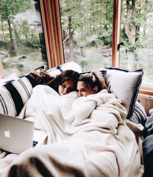 Amigas recostadas en sofá viendo una película