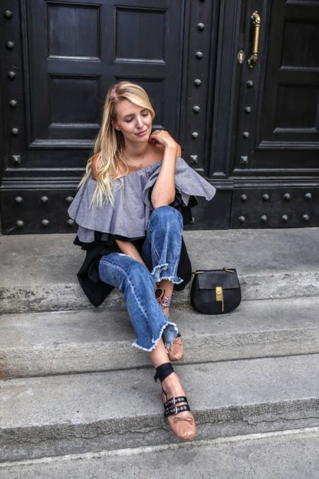 Mujer de cabello rubio y largo con pantalón de mezclilla y blusa gris con ballerinas de Miu Miu