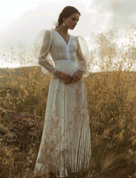 Mujer en pastizal con vestido de novia marfil de mangas gigot