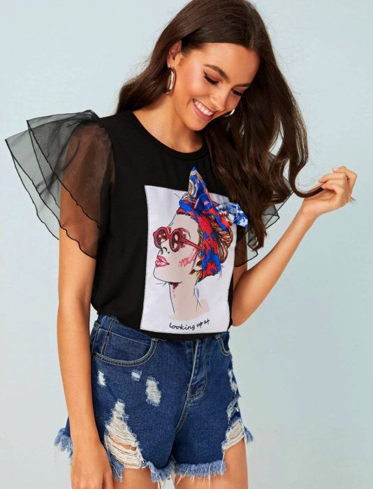 Mujer de cabello castaño con blusa estampada de mangas gigot y short desgastado