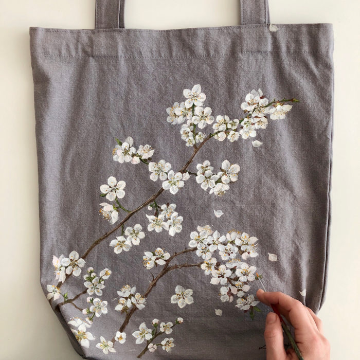 Bolsa tipo loneta color gris con hojas y flores blancas