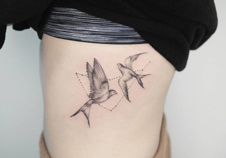 Tatuaje de la constelación de capricornio con dos golondrinas en el área lateral del abdomen