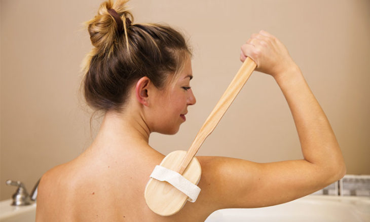 Mujer cepillando su piel con cepillo de cerdas suaves