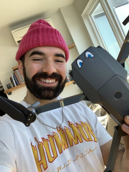 Chico tomando su dron para enviar un mensaje a una chica frente a su edificio 