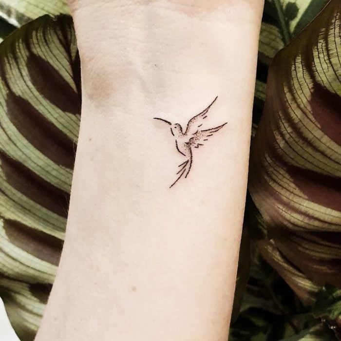 Tatuaje al estilo hand poke de un colibrí en el área de la muñeca